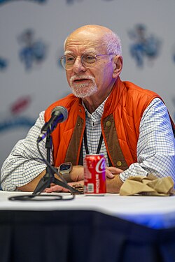 Claremont seated and talking with his arms crossed