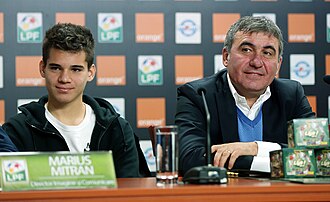 A young man and an older man sitting at a desk with a microphone