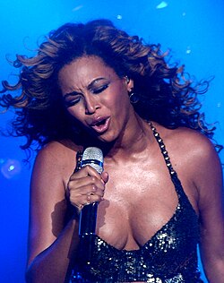 The upper body of Beyoncé is shown as she sings into a microphone.