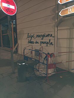 Graffiti reading "Luigi Mangione, hero of the people" in French, spray-painted with black cursive letters, in Marseille, France.