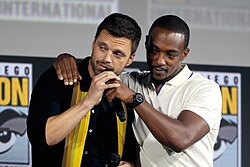 Two men attending a convention, one of whom is speaking into a microphone.