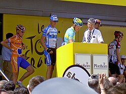 A group of cyclists on a stage near a podium.